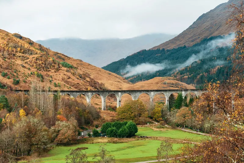 The Glenfinnan Viaduct arching over the glen with the Jacobite Steam Train crossing on a Glenfinnan viaduct tour from Edinburgh, Scottish Highlands