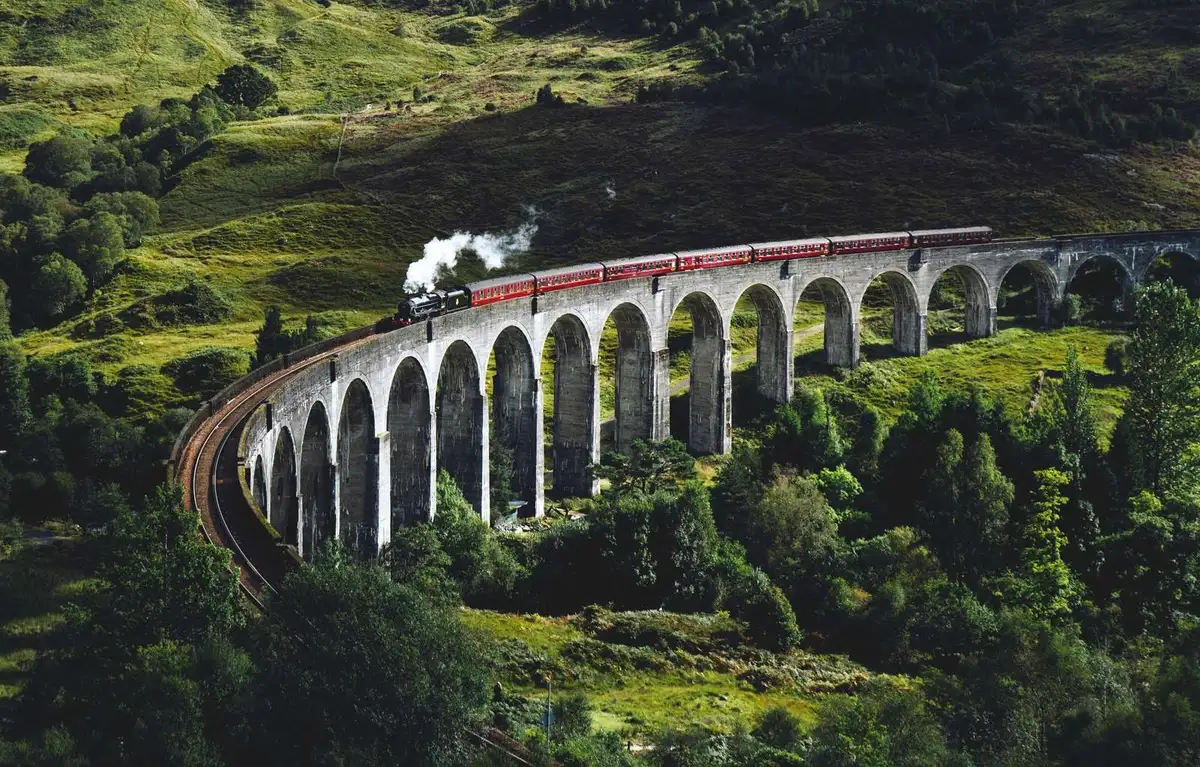 Aerial view of a steam train curving across the Glenfinnan Viaduct, the signature sight of every Glenfinnan Viaduct tour in the Scottish Highlands